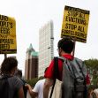 Protesters holding signs advocating for rent relief and a halt to evictions, with a city skyline in the background. Protesters holding signs advocating for rent relief and a halt to evictions, with a city skyline in the background.