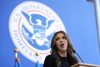 A woman speaking at a podium in front of the U.S. Department of Homeland Security seal.