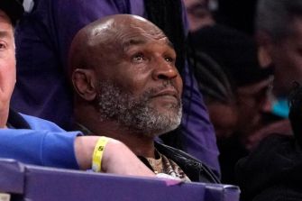 Mike Tyson sitting in the audience at a sporting event, looking contemplative.