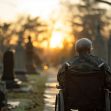 An elderly veteran in a wheelchair sitting in a cemetery during sunset. An elderly veteran in a wheelchair sitting in a cemetery during sunset.