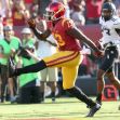 A football player in a USC uniform running on the field during a game. A football player in a USC uniform running on the field during a game.