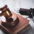 A gavel resting on a law book next to a handgun and cash, symbolizing legal and financial aspects of gun ownership. A gavel resting on a law book next to a handgun and cash, symbolizing legal and financial aspects of gun ownership.