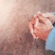 Elderly hands clasped together on a wooden surface, symbolizing contemplation or concern. Elderly hands clasped together on a wooden surface, symbolizing contemplation or concern.