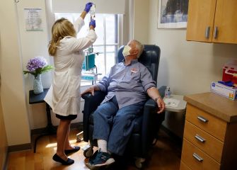 A healthcare professional administering an intravenous treatment to a patient in a medical facility.