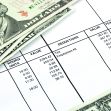 A close-up view of a payroll document alongside U.S. dollar bills. A close-up view of a payroll document alongside U.S. dollar bills.