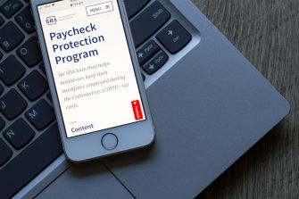 Image of a smartphone displaying information about the Paycheck Protection Program on a laptop keyboard.