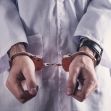 A doctor in handcuffs wearing a white medical coat. A doctor in handcuffs wearing a white medical coat.