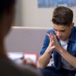 A young person sitting in a therapy session, looking contemplative and concerned. A young person sitting in a therapy session, looking contemplative and concerned.