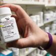 A hand holding a prescription bottle of OxyContin, a powerful opioid medication, with labels visible on the bottle. A hand holding a prescription bottle of OxyContin, a powerful opioid medication, with labels visible on the bottle.