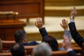 Members of Congress raising their hands to vote during a legislative session.