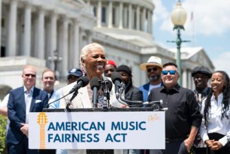 Dionne Warwick speaking at a press conference for the American Music Fairness Act, with a group of supporters in the background, outside the U.S. Capitol.