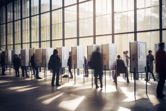 A group of people casting their votes at voting booths in a well-lit polling station.