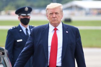 Donald Trump walking away from a vehicle, with an Air Force officer in the background.