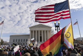 A crowd gathers outside the Supreme Court building, with American and pride flags visible, as oral arguments are presented regarding Tennessee's transgender law.