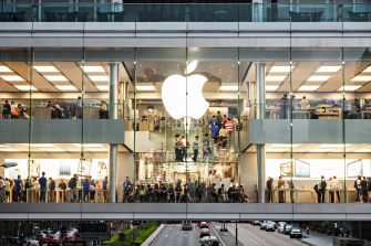 Apple store front with customers browsing and interacting with products.