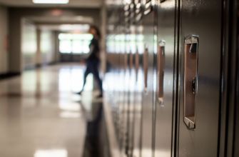 A blurry view of school lockers with a student standing in the background, indicating a school environment.