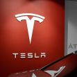 Tesla logo on a red wall in a dealership. Tesla logo on a red wall in a dealership.