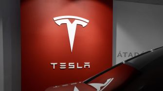 Tesla logo on a red wall in a dealership.
