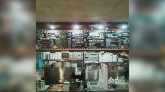 Menu board and kitchen area of Taqueria Garibaldi, a California-based taqueria.