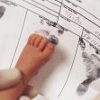 A close-up of a newborn's foot on a birth certificate, showing printed footprints and registration details. A close-up of a newborn's foot on a birth certificate, showing printed footprints and registration details.