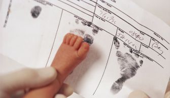A close-up of a newborn's foot on a birth certificate, showing printed footprints and registration details.