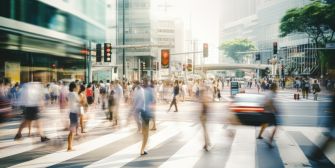 A busy urban crosswalk with blurred pedestrian traffic and a car approaching, highlighting various movement in the scene.