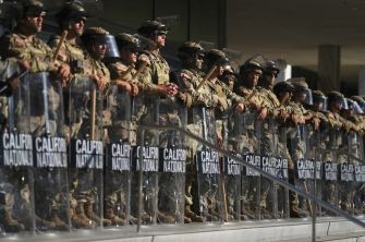 California National Guard members in tactical gear standing behind shields marked "California National."