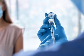 Medical professional preparing a vaccine for a patient during the COVID-19 pandemic.