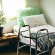 A nursing home's interior room featuring a bed with colorful blankets, a walker, a potted plant, and a small table with items, highlighting the environment where elderly care takes place. A nursing home's interior room featuring a bed with colorful blankets, a walker, a potted plant, and a small table with items, highlighting the environment where elderly care takes place.