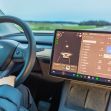 Interior view of a Tesla vehicle showing the steering wheel and dashboard display with driver assistance features activated. Interior view of a Tesla vehicle showing the steering wheel and dashboard display with driver assistance features activated.