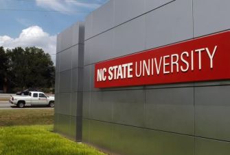 Signage of North Carolina State University (NC State) along a roadside.