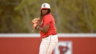 A baseball player in a red uniform on the pitcher's mound during a game.