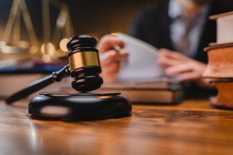 A gavel placed on a wooden table with legal books in the background, symbolizing a court case and legal proceedings.