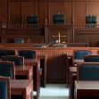 An empty courtroom with wooden benches and a judge's bench in the background. An empty courtroom with wooden benches and a judge's bench in the background.