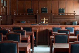 An empty courtroom with wooden benches and a judge's bench in the background.