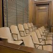 A row of jury seats in a courtroom, showing wooden walls and blinds. A row of jury seats in a courtroom, showing wooden walls and blinds.