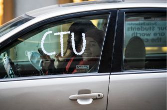 A person inside a car smiling and holding up a peace sign, with the letters "CTU" written on the window.