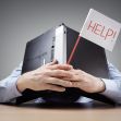 A person hiding behind a laptop, holding a sign that says "HELP!" A person hiding behind a laptop, holding a sign that says "HELP!"