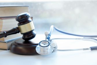 A gavel resting on a stack of law books beside a stethoscope, symbolizing the intersection of law and medicine in a medical malpractice case.