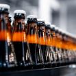 A row of beverage bottles on a production line in a factory setting. A row of beverage bottles on a production line in a factory setting.