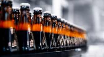 A row of beverage bottles on a production line in a factory setting.