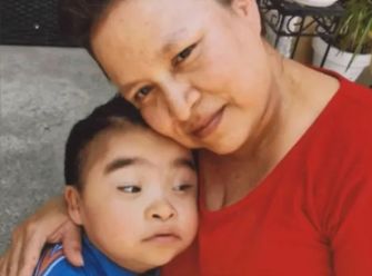 A woman embraces a young boy, both displaying affection, with the boy appearing to have special needs.