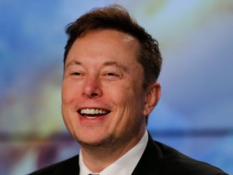 Image of a man smiling in a suit, with a blurred background.