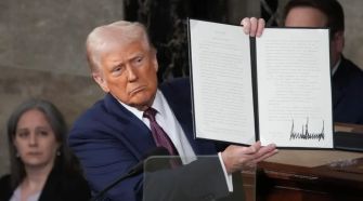 Former President Trump holding up an executive order during a press event.