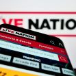 A smartphone displaying the Live Nation app with a logo in the background. A smartphone displaying the Live Nation app with a logo in the background.