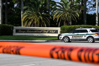 Police vehicle parked in front of Trump International Golf Club with police tape in the foreground.