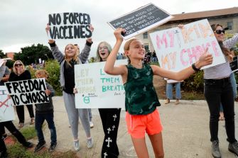 A group of protesters holding signs advocating for freedom of choice regarding vaccinations during a demonstration.