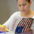 A person studying a citizenship civics and literacy guide with an American flag design on the cover. A person studying a citizenship civics and literacy guide with an American flag design on the cover.