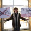 A student holding two signs outside a school, one crossed out with a building drawing and the other stating "MY RIGHTS ARE NON-NEGOTIABLE." A student holding two signs outside a school, one crossed out with a building drawing and the other stating "MY RIGHTS ARE NON-NEGOTIABLE."