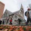 UMass campus scene with students walking and biking past a historic building during autumn. UMass campus scene with students walking and biking past a historic building during autumn.